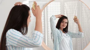 Vrouw spuit droogshampoo in haar haar.