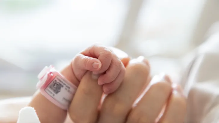 Foto van babyhandje dat vinger vasthoudt van moeder.