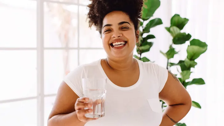 Healthy woman with glass of water at home