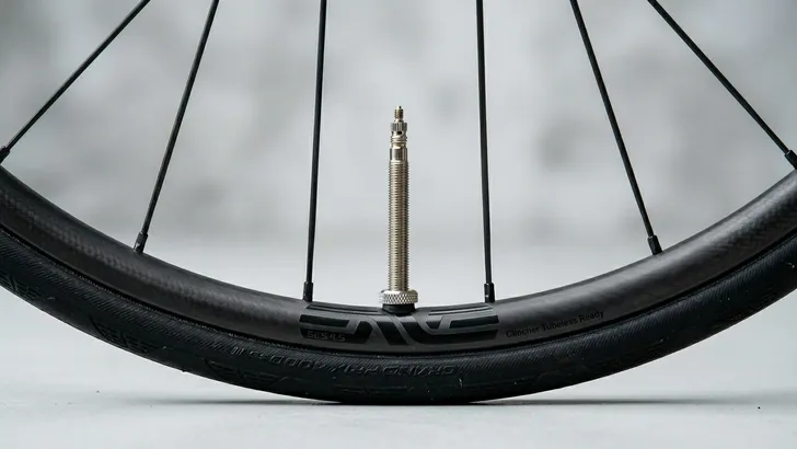 Close-up van een lage fietsvelg in een studio, waarbij het ventiel foutief en extreem ver (als een schoorsteen) uitsteekt.