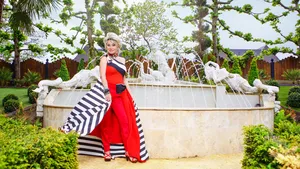 Foto van Marjan Strijbosch, bekend van The Real Housewives van het Zuiden, in een rode outfit bij een fontein.
