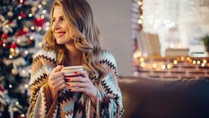 Portrait of woman in front of Christmas tree, drinking hot drink
