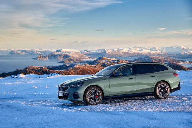BMW i5 Touring in een besneeuwd berglandschap