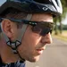 Close-up van een mannelijke wielrenner waarbij de poot van de fietsbril correct over de bandjes van de fietshelm wordt gedragen.