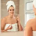 vrouw gewikkeld in handdoek in de badkamer spuit parfum op