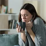 Angry woman getting cold holding coffee mug at home