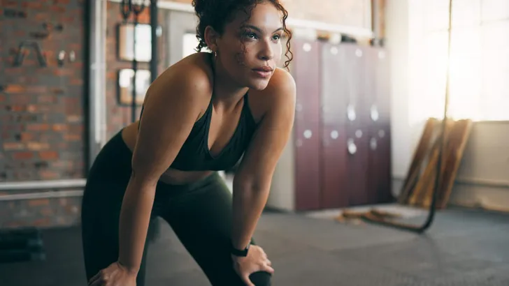 Tired, exercise and woman at gym after fitness workout or training for health and body wellness. Young sports female or athlete resting on break while thinking about goals, progress and performance
