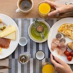 Unrecognizable woman waiting for breakfast with orange juice, coffee and eggs