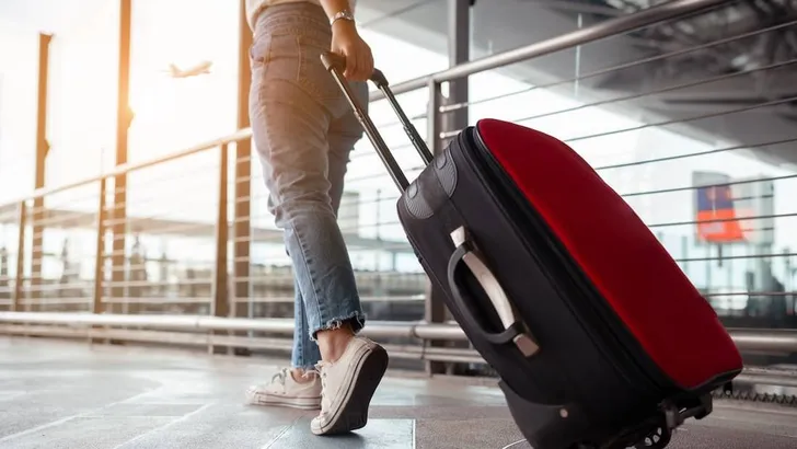 Traveler with suitcase in airport concept.Young girl walking with carrying luggage and passenger for tour travel booking ticket flight at international vacation time in holiday rest and relaxation.