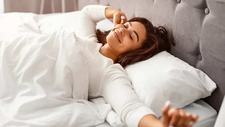 Happy young African American woman stretching arms after waking up