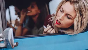 Women on road trip doing makeup in a moving car