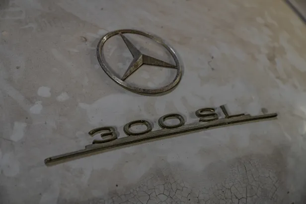 Mercedes-ster en 300 SL-embleem op verweerde grijze carrosserie