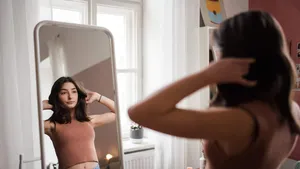 Young teenage girl looking in the mirror in her room.