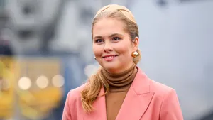 Amalia lachend in roze jas en beige trui met haarband in haar