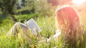 girl reading book in the field