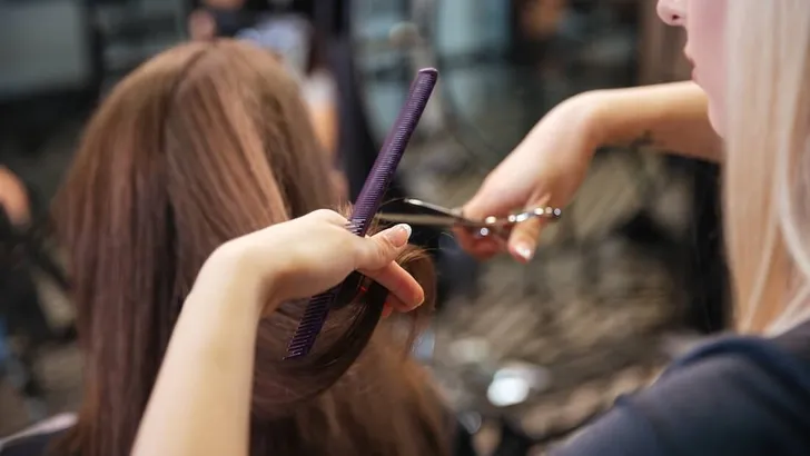 Beautiful hairdresser doing hairstyle to her client in beauty salon