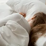 Female sleep on white sheets relaxing in cozy bedroom