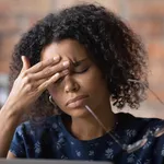 Frustrated black female freelancer overworked by computer feel headache migraine