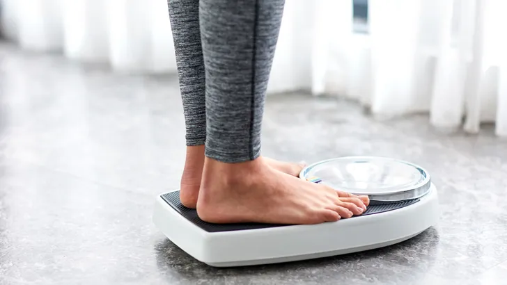 Young healthy girl on home scales