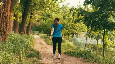 Een actieve vrouw wandelt overdag over een pad in het bos.