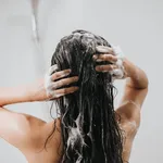 Woman washing hair with shampoo and shower in bathroom, Asian female body and hair care with foam to freshness. Spa and Health care.