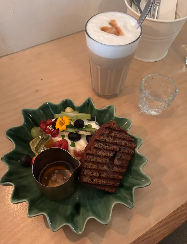 Bananenbrood met vers fruit en Griekse yoghurt en een kop koffie op tafel.