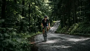 Eenzame wielrenner bedwingt een steile, smalle klim in een donker bos in de Ardennen.