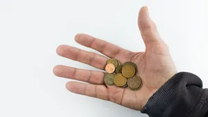 Ter illustratie: man met een aantal muntjes in zijn hand