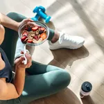 Athletic woman eating a healthy bowl of muesli with fruit sittin