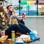 Couple sitting on the supermarket floor and eating snacks