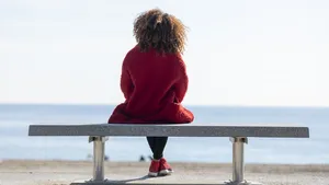 vrouw bankje alleen krullen rode jas