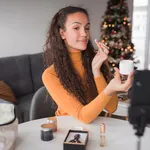 Beauty blogger using moisturizer and making a live stream while doing so