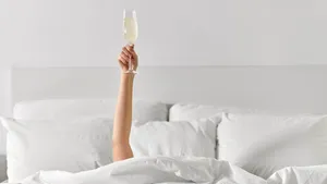 hand of woman lying in bed with champagne glass