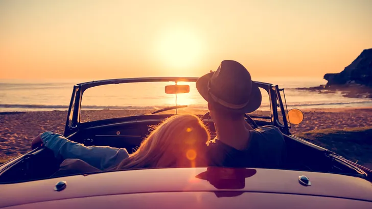 Couple watching the sunset in a convertible car.