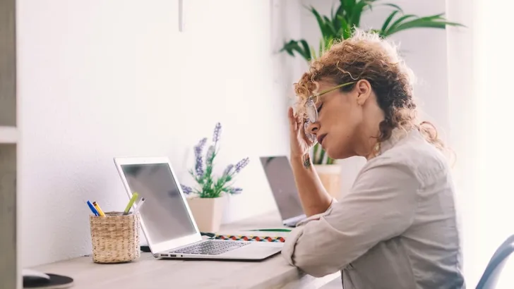 Sick exhausted Caucasian female work on laptop struggle with migraine or headache. Tired unwell young woman take off glasses overwhelmed with computer job suffer from blurry vision or dizziness.