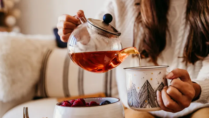 Een vrouw die thee inschenkt