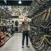 Een man staat met zijn handen in het haar van keuzestress in een overvolle fietsenwinkel, omringd door rekken vol gravelbikes en accessoires.