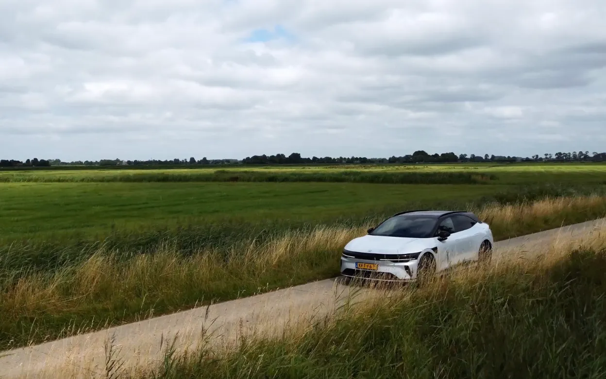 Zeekr 7GT rijdend over een smalle weg door het Nederlandse polderlandschap