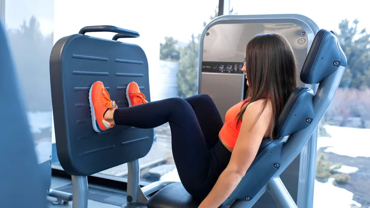 Vrouw in de sportschool doet leg press tijdens het trainen van de grote spieren.