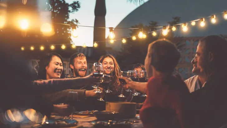 Happy family dining and tasting red wine glasses in barbecue dinner party - People with different ages and ethnicity having fun together - Youth and elderly parents and food weekend activities concept