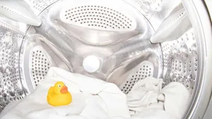 Een gele badeend samen met beddengoed in een wasmachine trommel