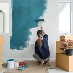 Young asian happy woman painting interior wall