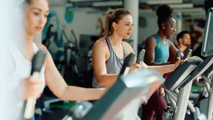 Group of athletes exercising on cross trainer while working out in gym.