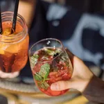 Women holding glasses of summer cocktails and toasting. Healthy lifestyle concept. Outdoors.