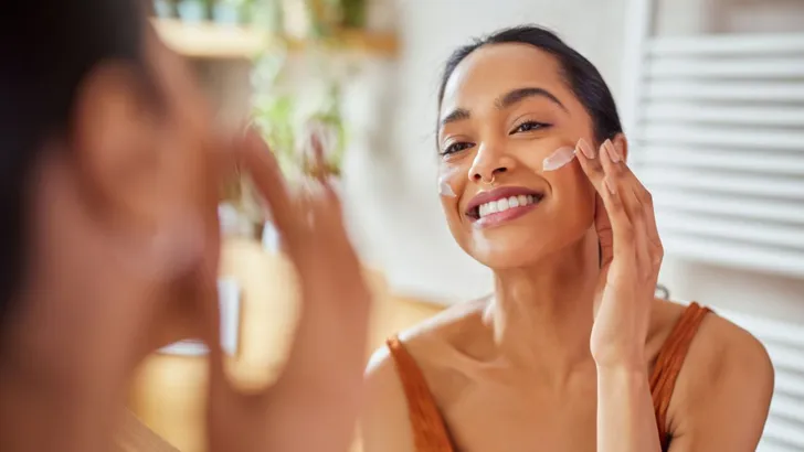 Vrouw brengt skincare aan voor glowy huid.