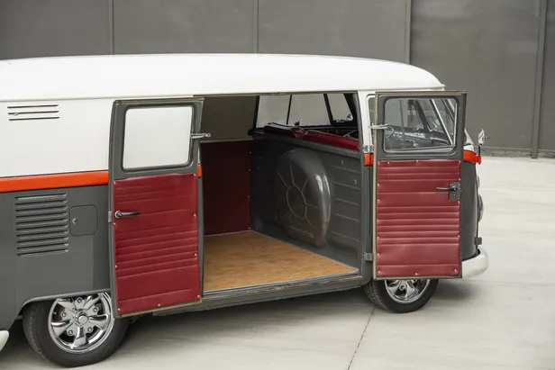 Geopende laaddeuren van de Volkswagen-bus tonen de laadruimte met houten vloer en reservewiel.