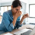 Stressed business woman working from home on laptop looking worried, tired and overwhelmed.