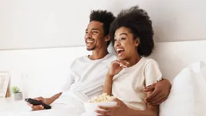 Couple sitting in bed together eating popcorn