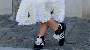Vrouw met donkerbruine sneakers met witte strepen