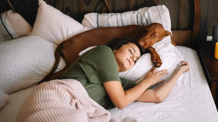 Girl with dog in bed. Best friends sleeping together.